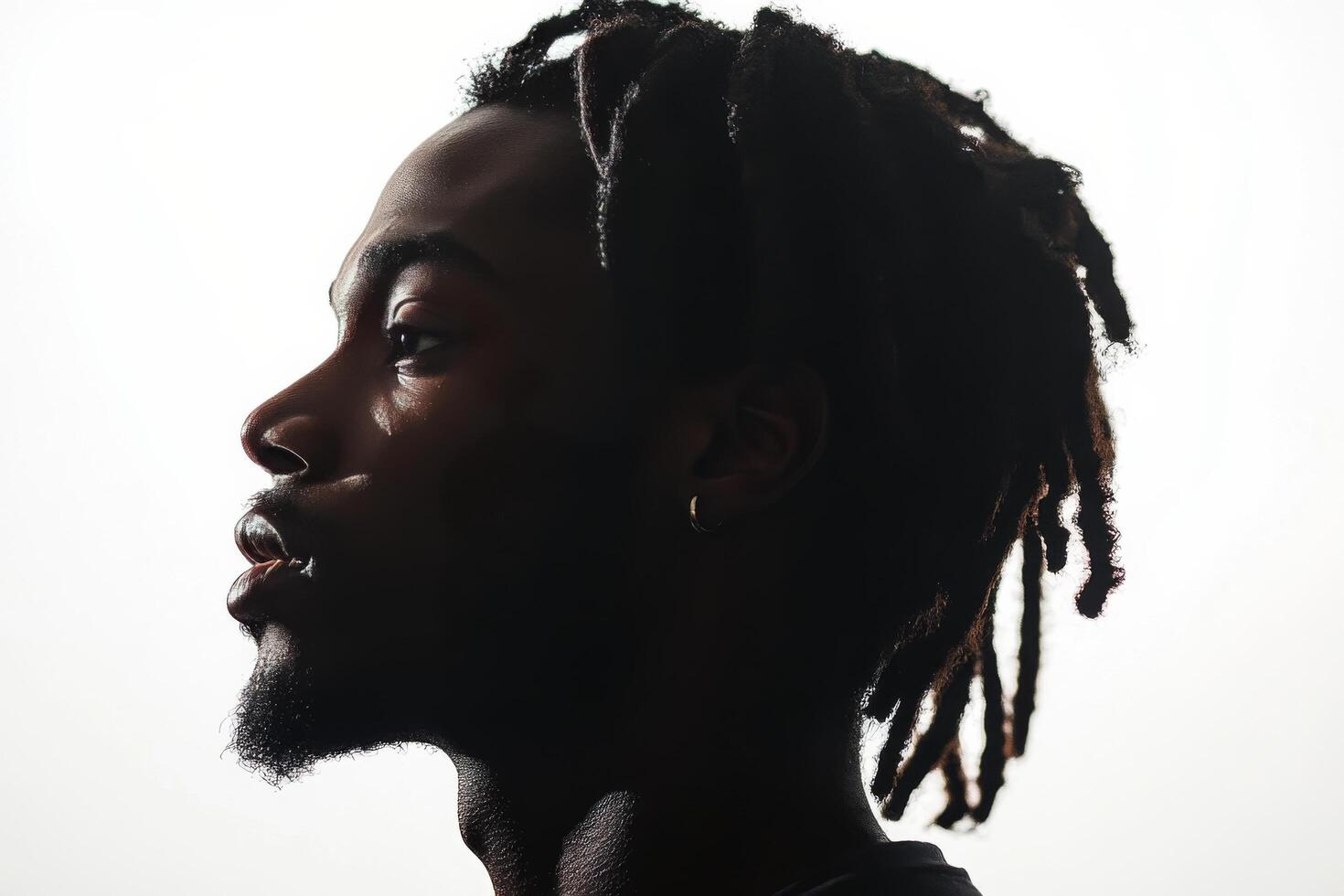 Profile of a man with dreadlocks against a bright background showcasing his thoughtful expression photo