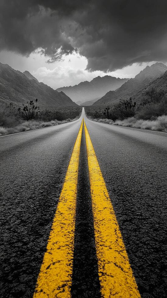 A winding road leads through mountain passes under a dramatic cloudy sky in a remote landscape photo