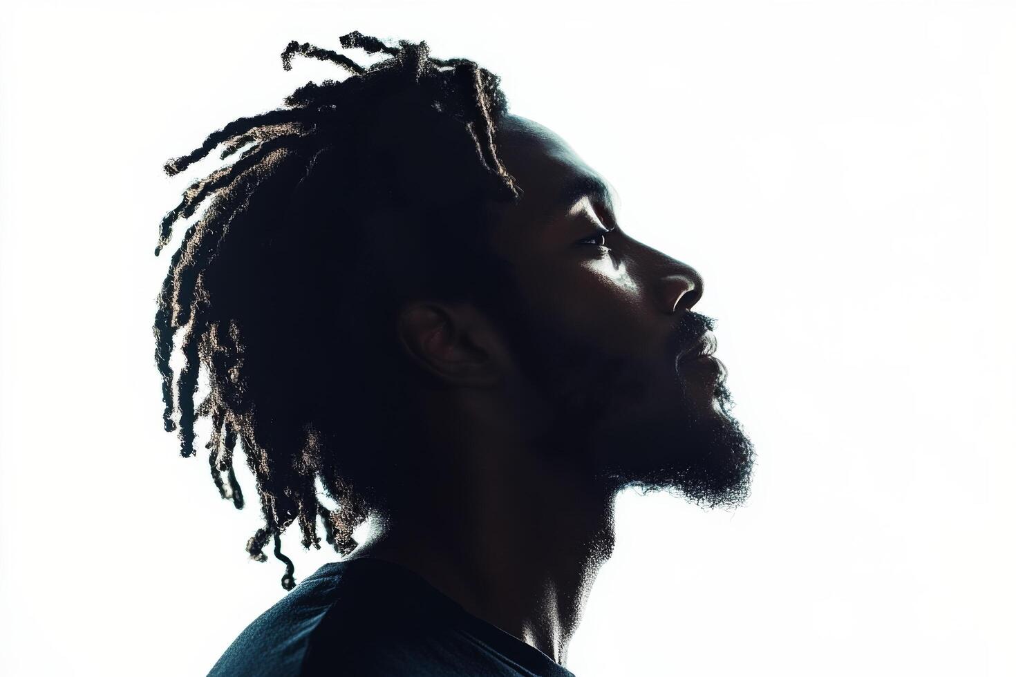 Profile of a man with dreadlocks against a bright background showcasing his thoughtful expression photo
