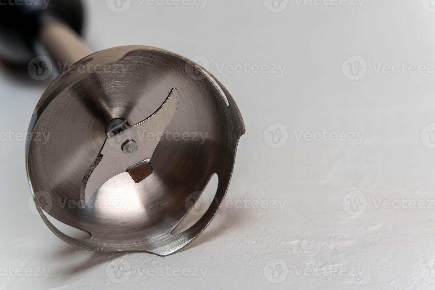 Stainless steel blender attachment resting on a light surface photo