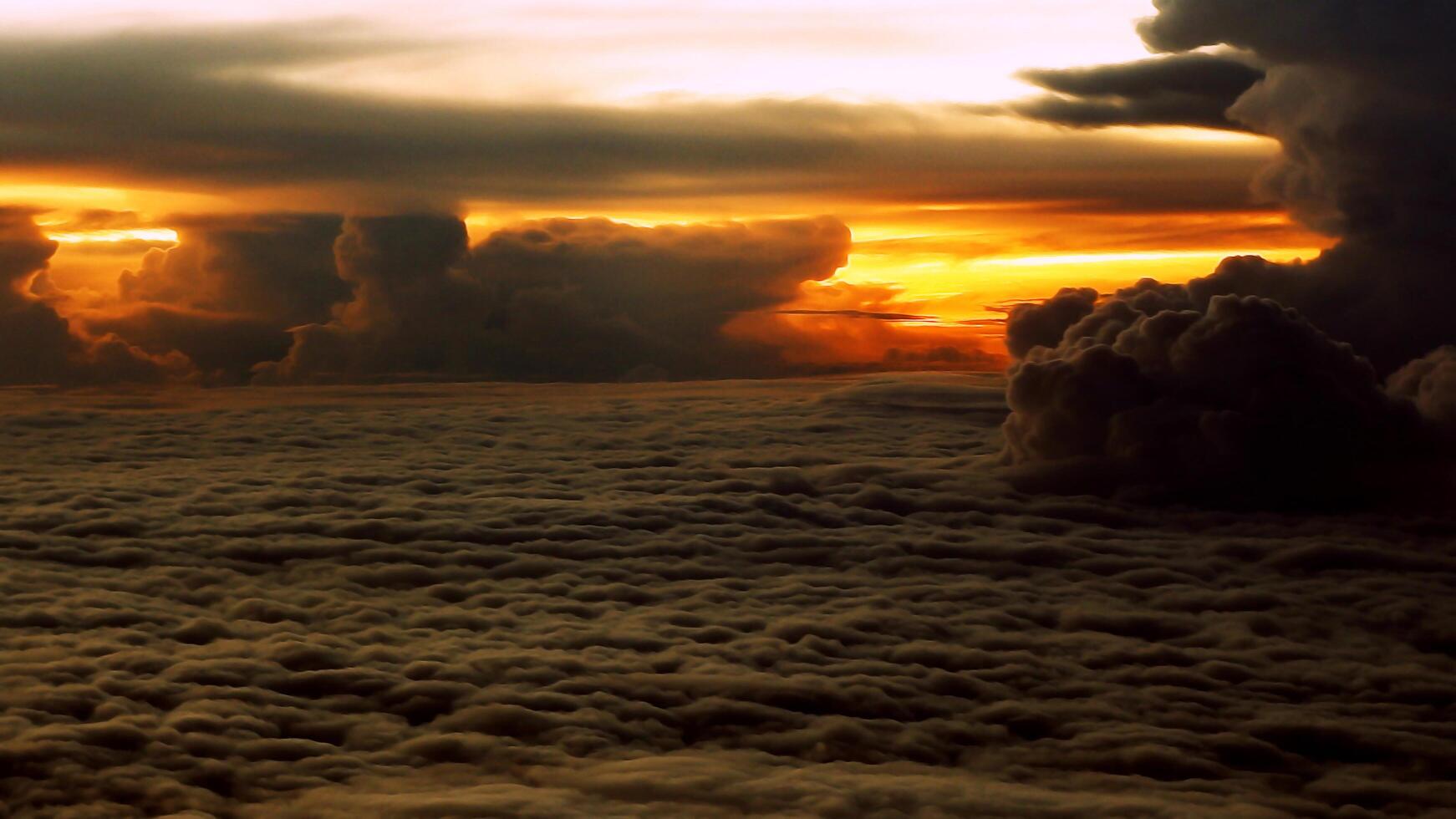 View of the sunset above the clouds as seen from inside the plane photo