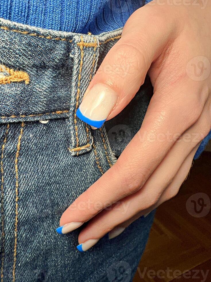 Chic blue-tipped manicure paired with denim in a cozy setting photo