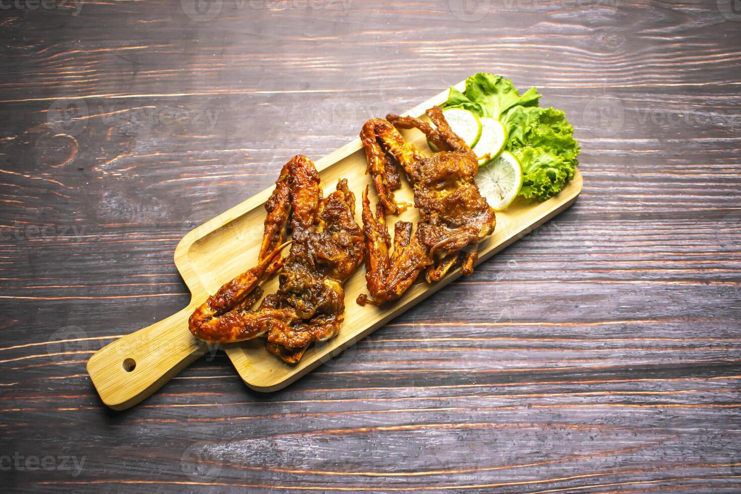 Fried Crab Masala with lettuce leaves and lemon slice served on wooden board isolated on wooden table top view of bangladeshi and thai food photo