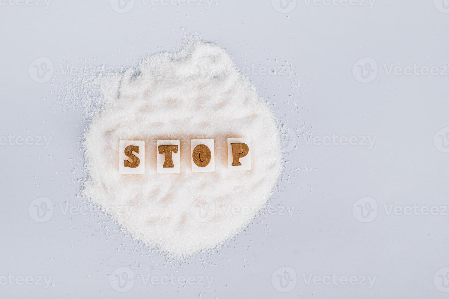 The word stop on pieces of refined sugar on granulated sugar on a blue background, top view photo