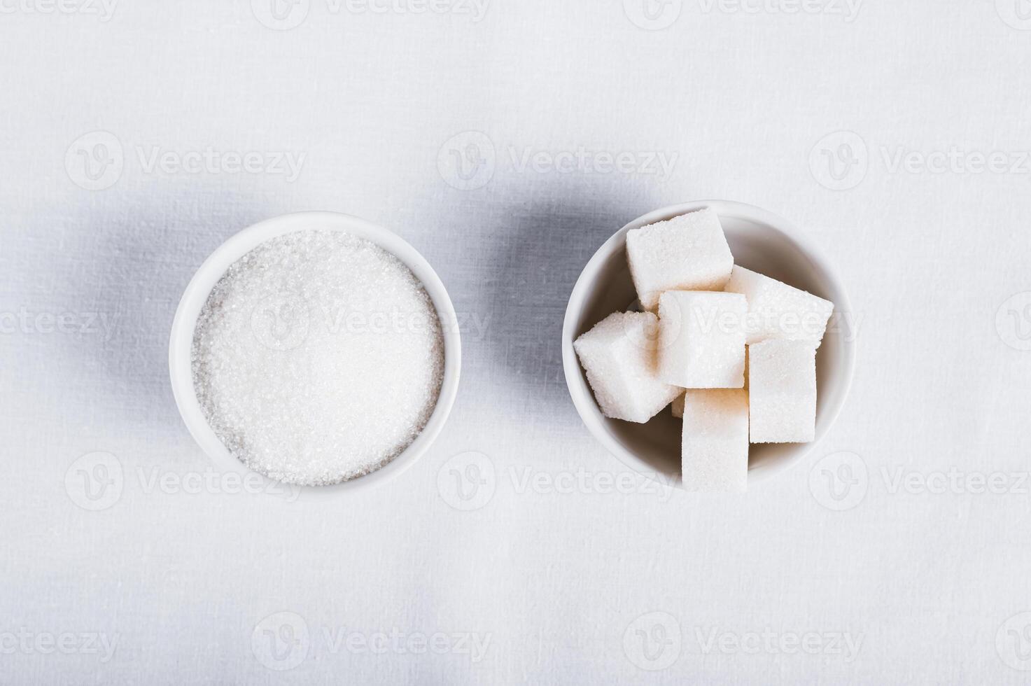 Choosing between granulated sugar and refined sugar in bowls on white background photo