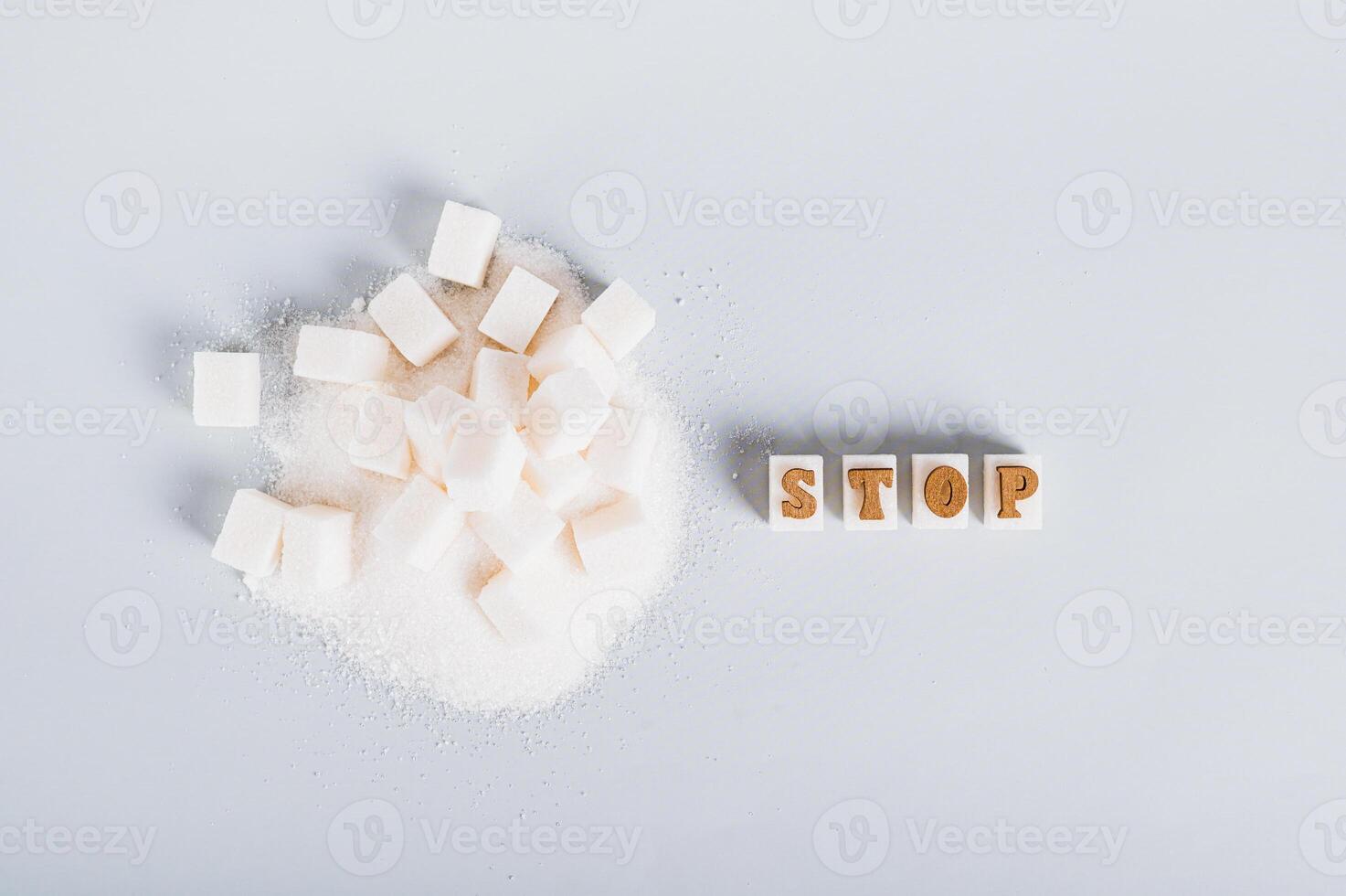 The word stop on pieces of refined sugar as a symbol of refusal from sugar on a blue background photo