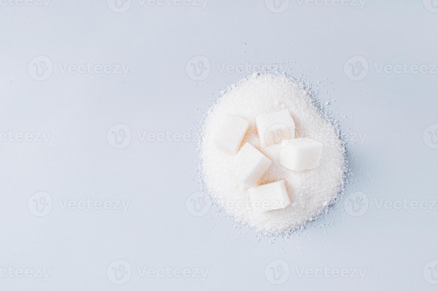 Lump sugar on a pile of granulated sugar on a blue background top view copy space photo