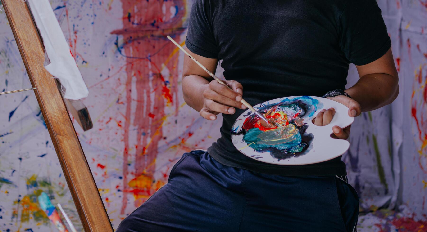 Close up of asian male painter at work painting on canvas in art studio. Creation and inspiration at an artists painting studio. photo