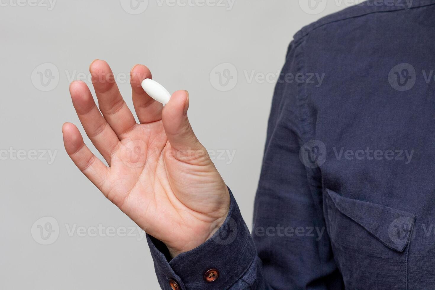 Woman hand holding white big pill photo