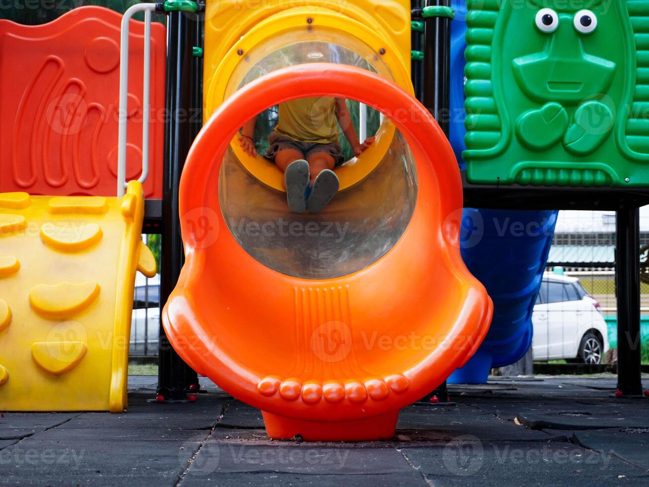 Children playing in the playground during summer vacation. Cute girl having fun on a colorful slide in an outdoor park. photo