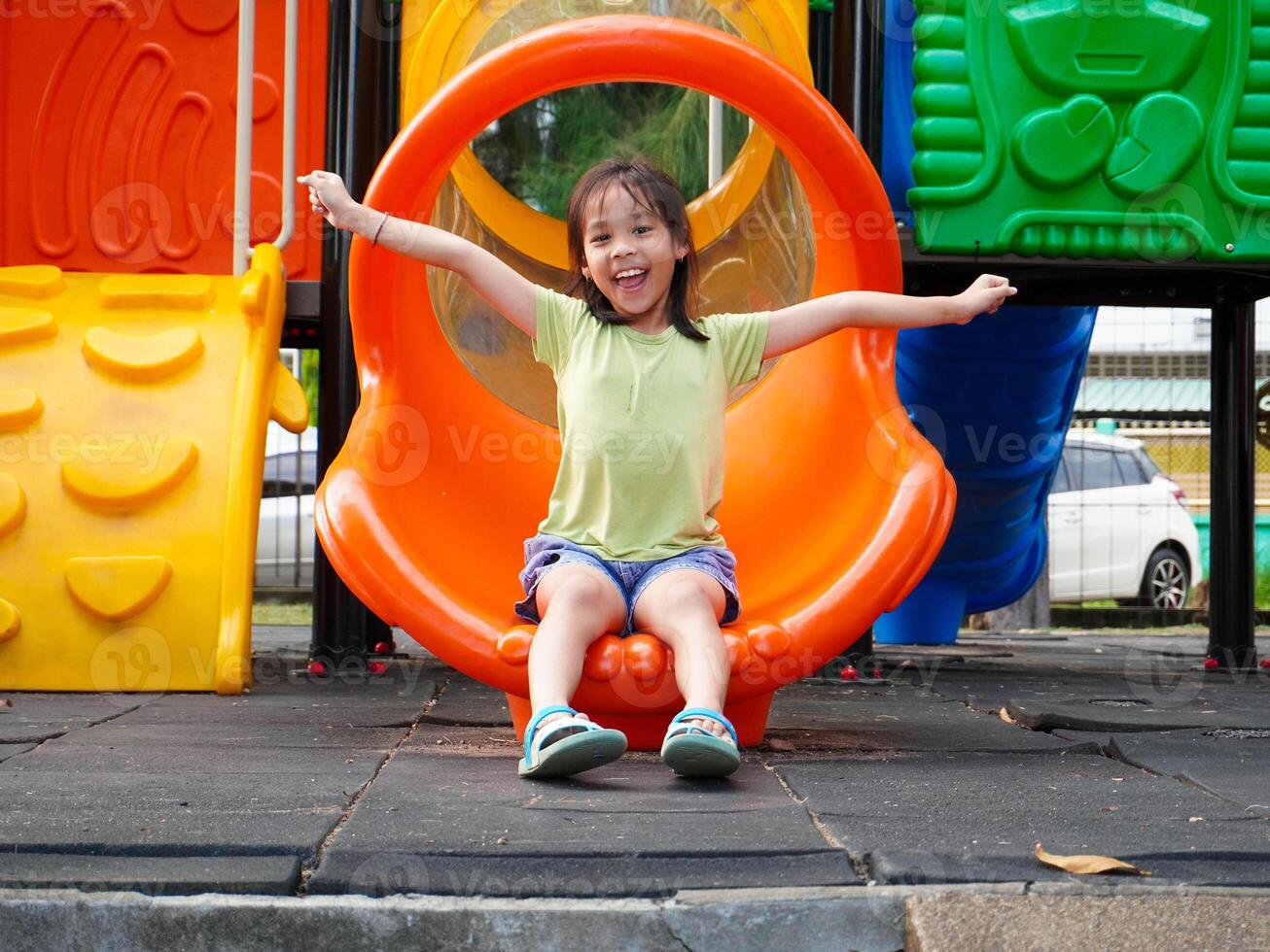 Children playing in the playground during summer vacation. Cute girl having fun on a colorful slide in an outdoor park. photo