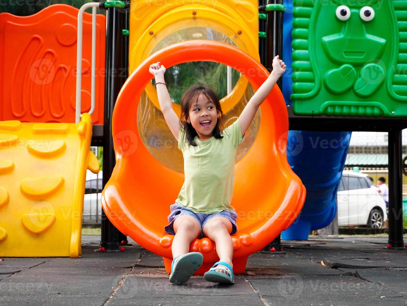 Children playing in the playground during summer vacation. Cute girl having fun on a colorful slide in an outdoor park. photo