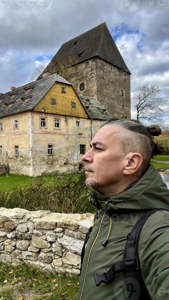 Tourist poses in front of Medieval knight's castle, Siedlicin tower in Poland, Lower Silesia photo
