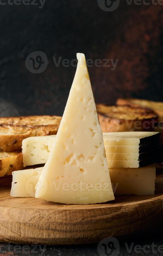 Triangular pieces of cheese and fried ciabatta slices on a wooden board photo