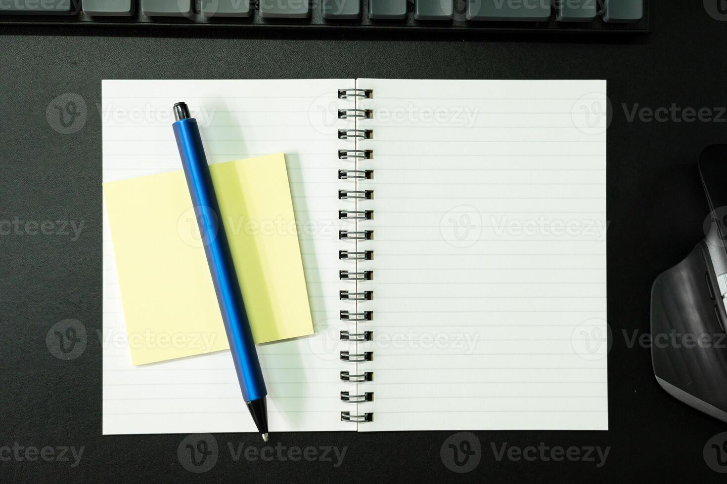 Top view of notebook. Blank paper notepad on office desk table with keyboard and other supplies. Blank notebook page for input the text. copy space, flat lay. photo