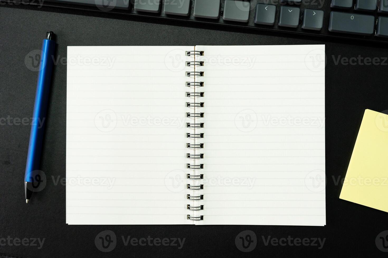 Top view of notebook. Blank paper notepad on office desk table with keyboard and other supplies. Blank notebook page for input the text. copy space, flat lay. photo