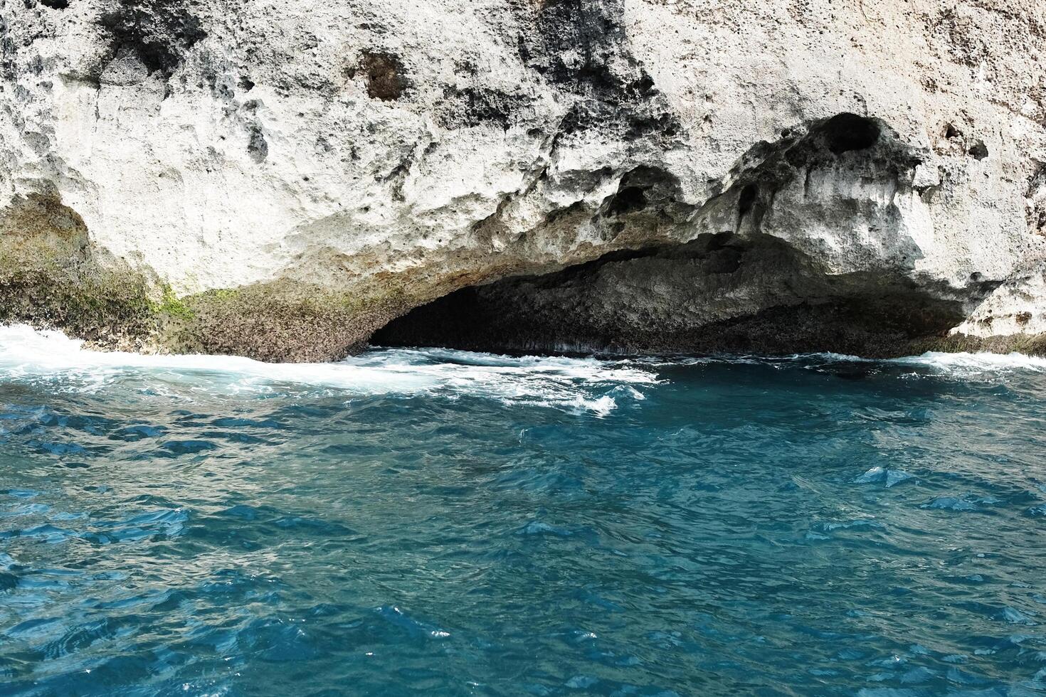 Landscape of rocky cliff at the sea with foam waves and splash water. Travel destination seascape of summer ocean in Bali island at Indonesia photo