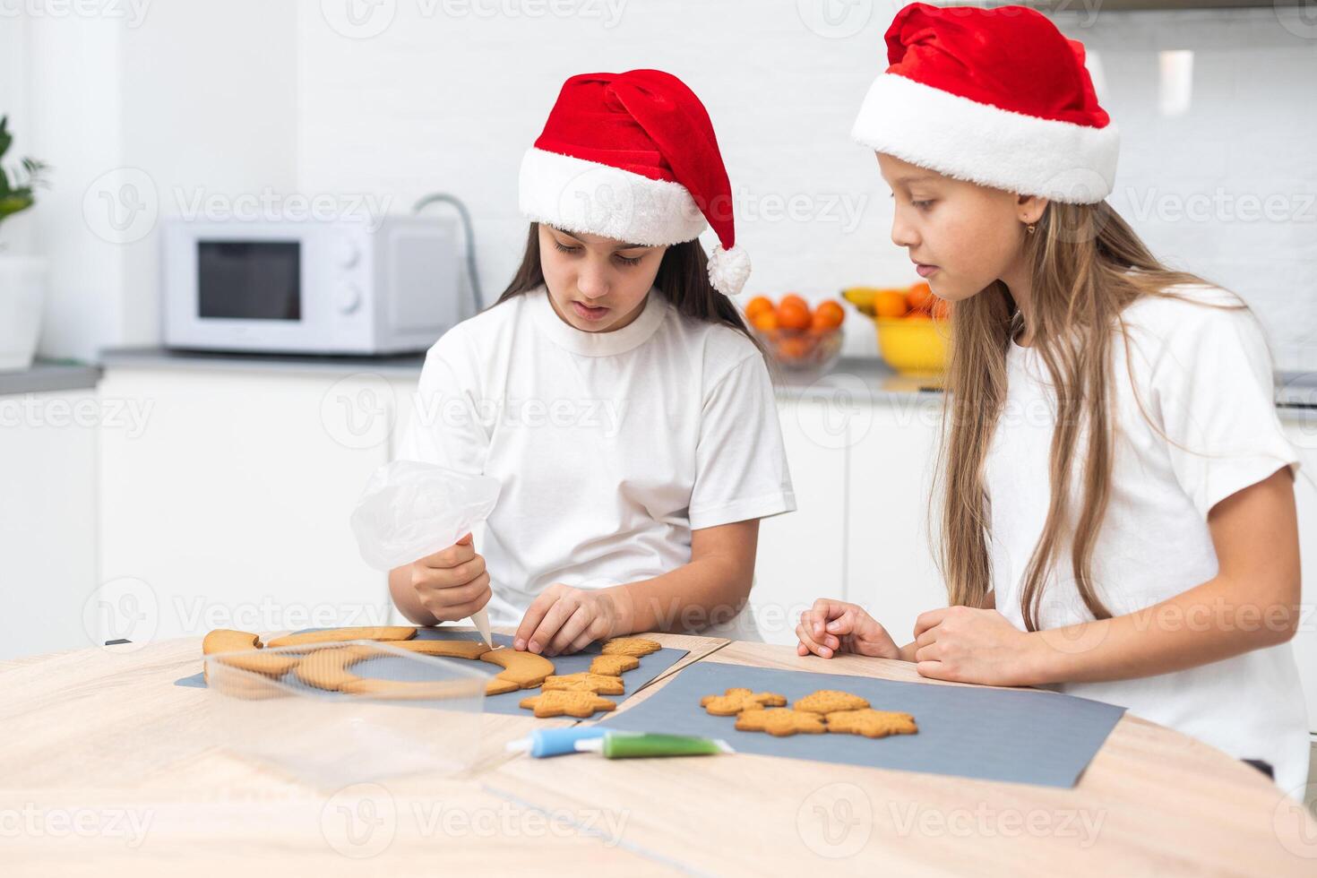 Two girls sisters are playing around in the kitchen after making Christmas cookies, they draw with flour on the table and on their faces. Christmas, New Year concept photo