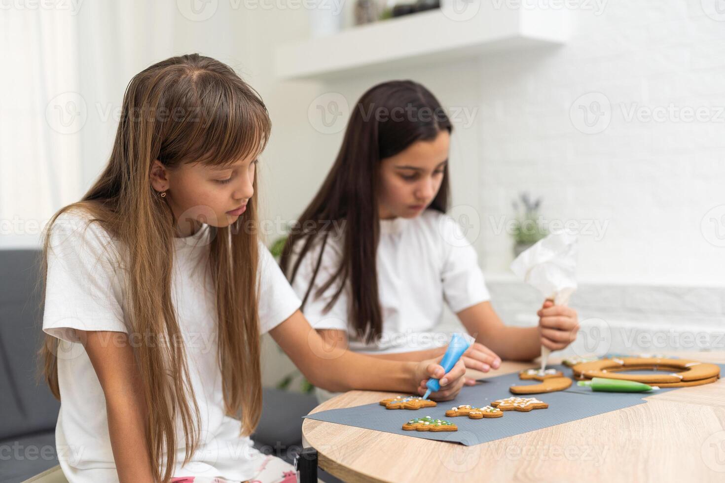 Two girls sisters are playing around in the kitchen after making Christmas cookies, they draw with flour on the table and on their faces. Christmas, New Year concept photo