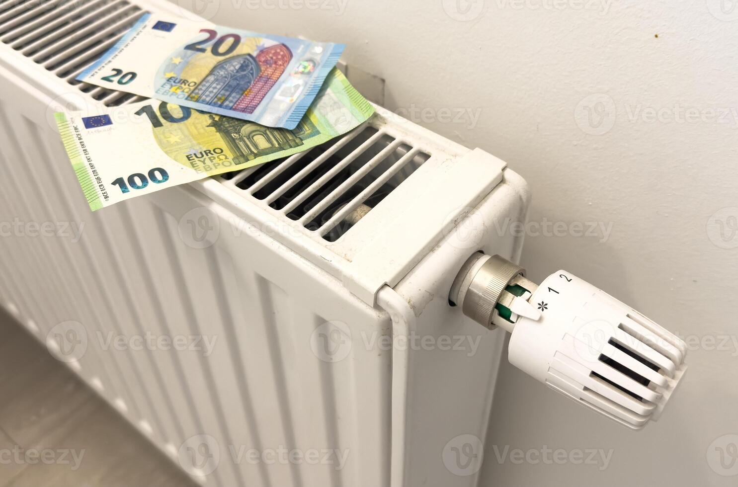 A heating radiator battery from which bills stick out. The concept of high heating expenses. Rise in energy prices, energy crisis and recession photo