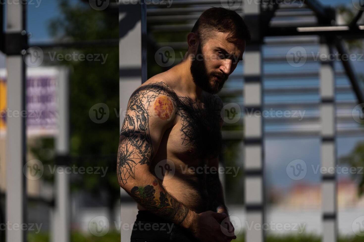 The young guy trains in the park on the street exercise machine photo