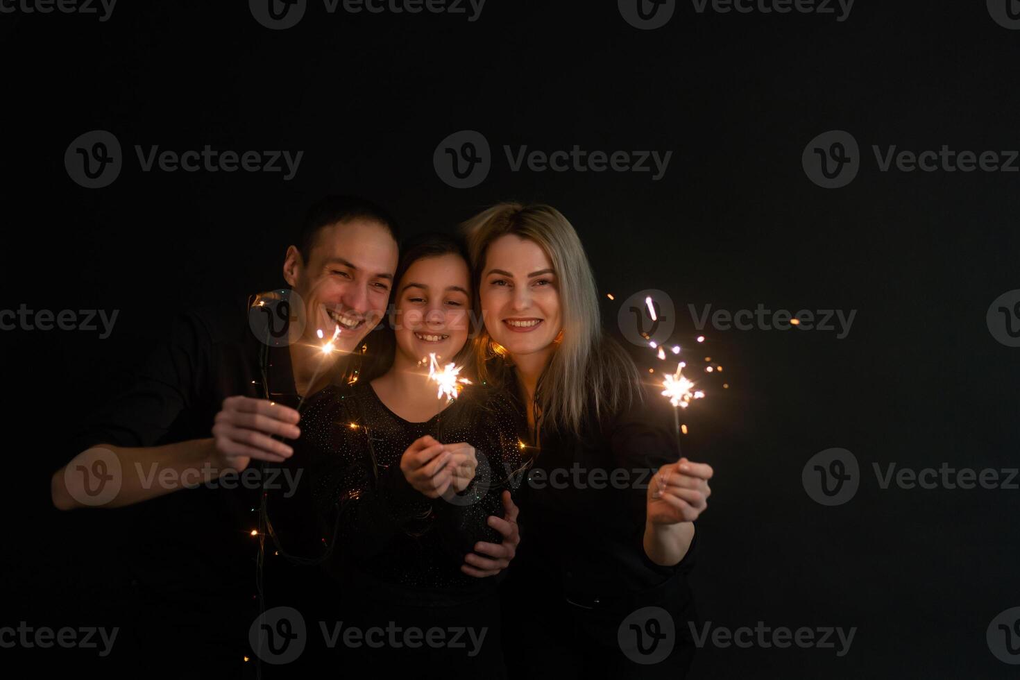 Young family with sparklers at Christmas time on a black background photo