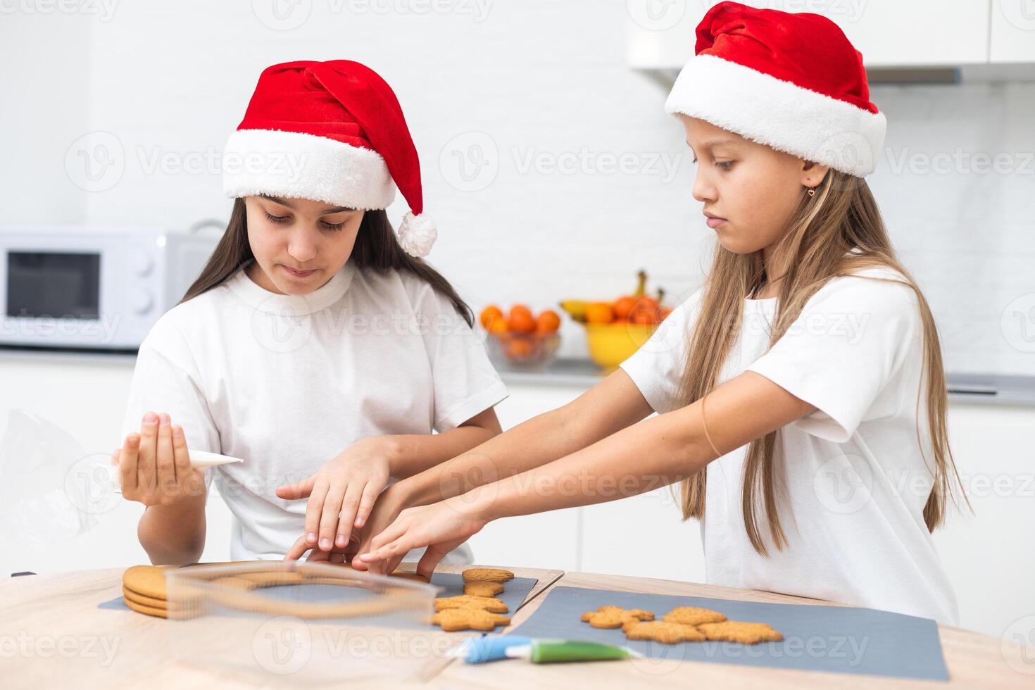 Two girls sisters are playing around in the kitchen after making Christmas cookies, they draw with flour on the table and on their faces. Christmas, New Year concept photo