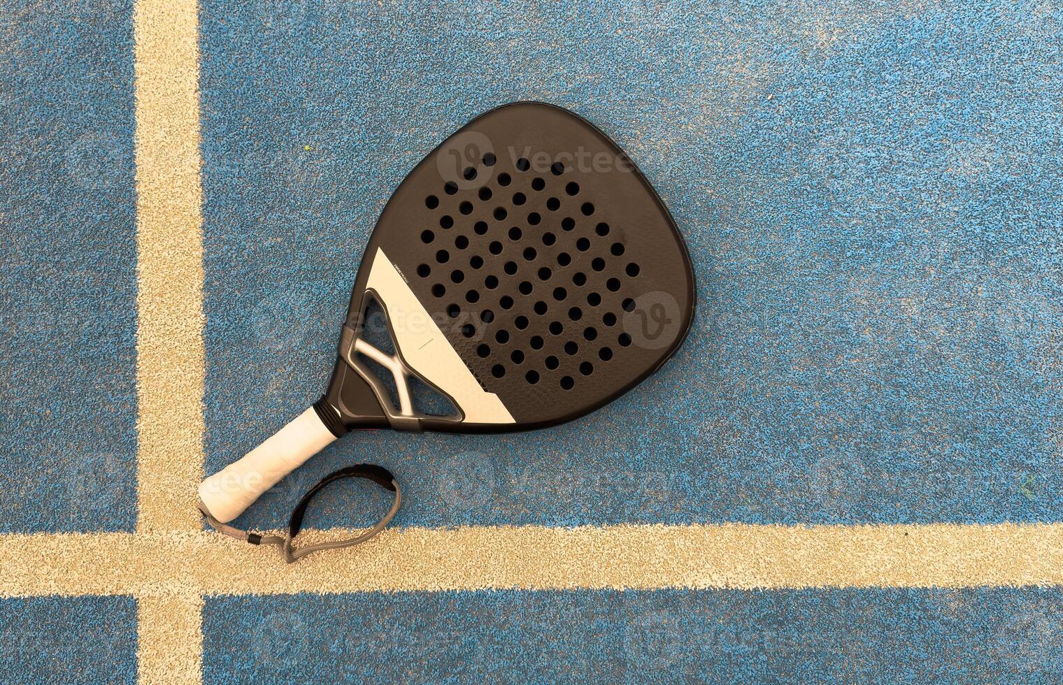 view from above of a green paddle racket and a ball on a blue synthetic paddle tennis court photo