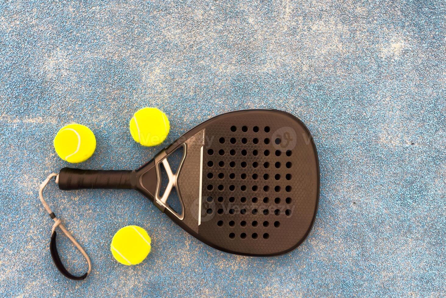 Paddle racket with a ball ready to play the fastest growing sport in recent years worldwide. Padel court in summer, the perfect time to practice this sporting discipline and release stress. photo