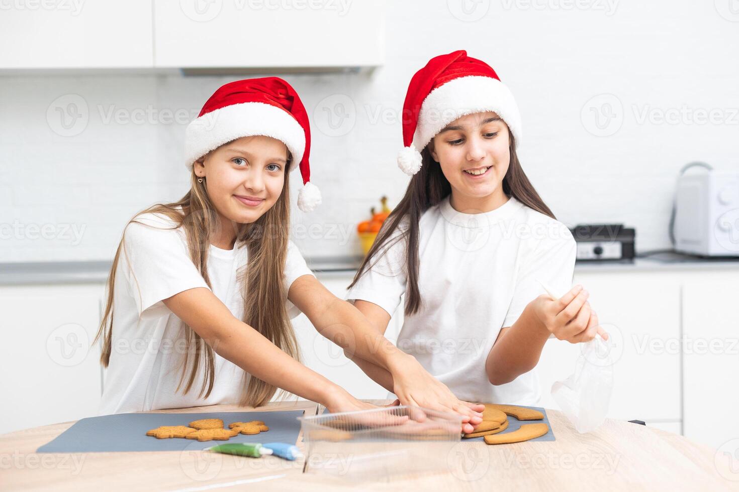 Two girls sisters are playing around in the kitchen after making Christmas cookies, they draw with flour on the table and on their faces. Christmas, New Year concept photo