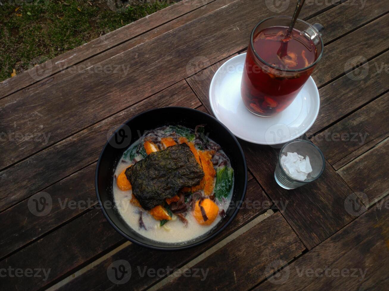 A top-down view of a ramen and traditional drinks served on a rustic wooden table. photo