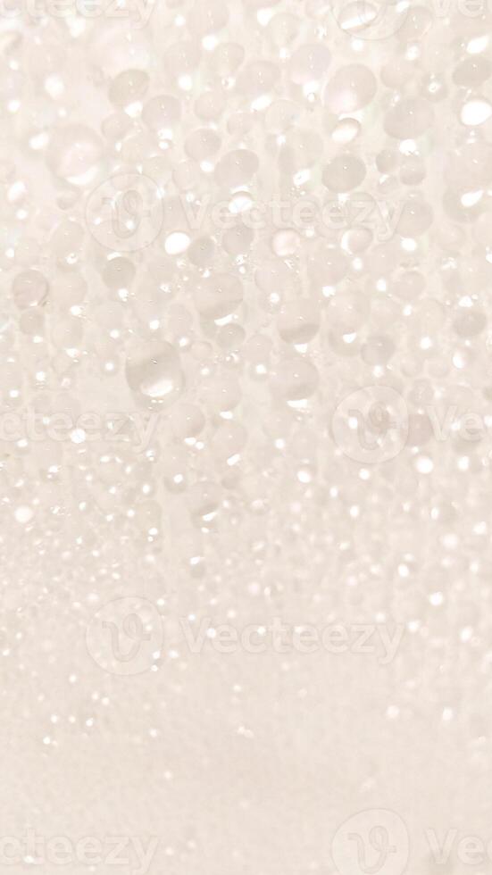 A close-up view of numerous water droplets on a transparent surface, creating a soft, dreamy texture with a white and pastel background. photo