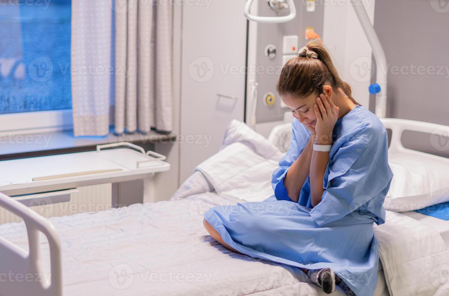 40-year-old woman sits alone in hospital bed in privat room,wiping tears from her eyes as she waits to see doctor, without support,expressing her concerns about the results of her examination, photo