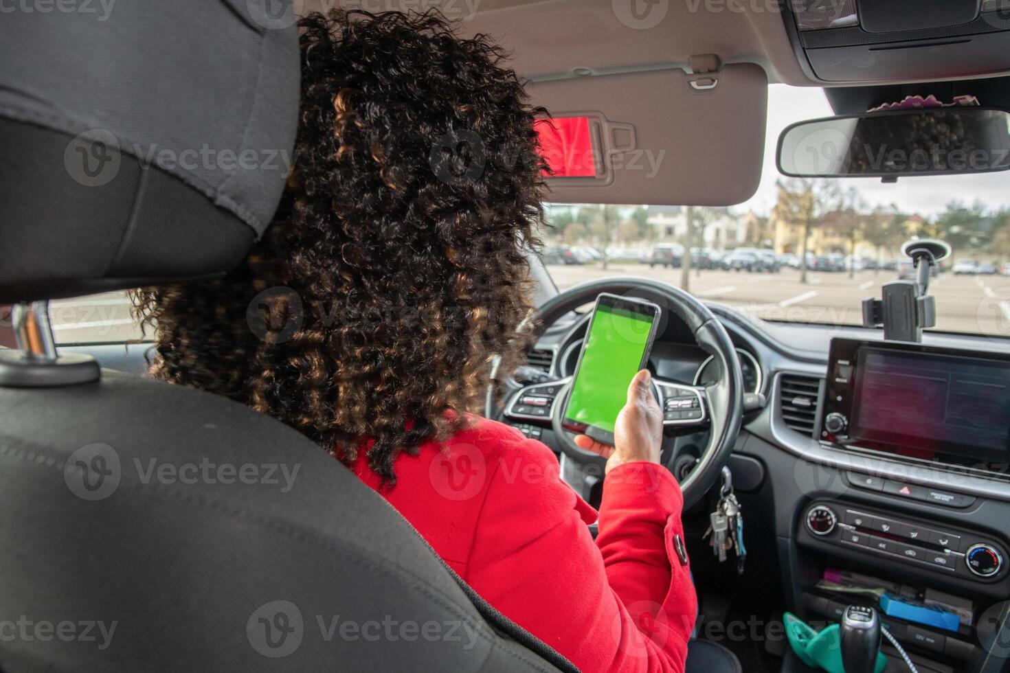 Satisfied young african american woman chatting in car with someone on mobile phone with green screen in parked car, using technology, High quality photo