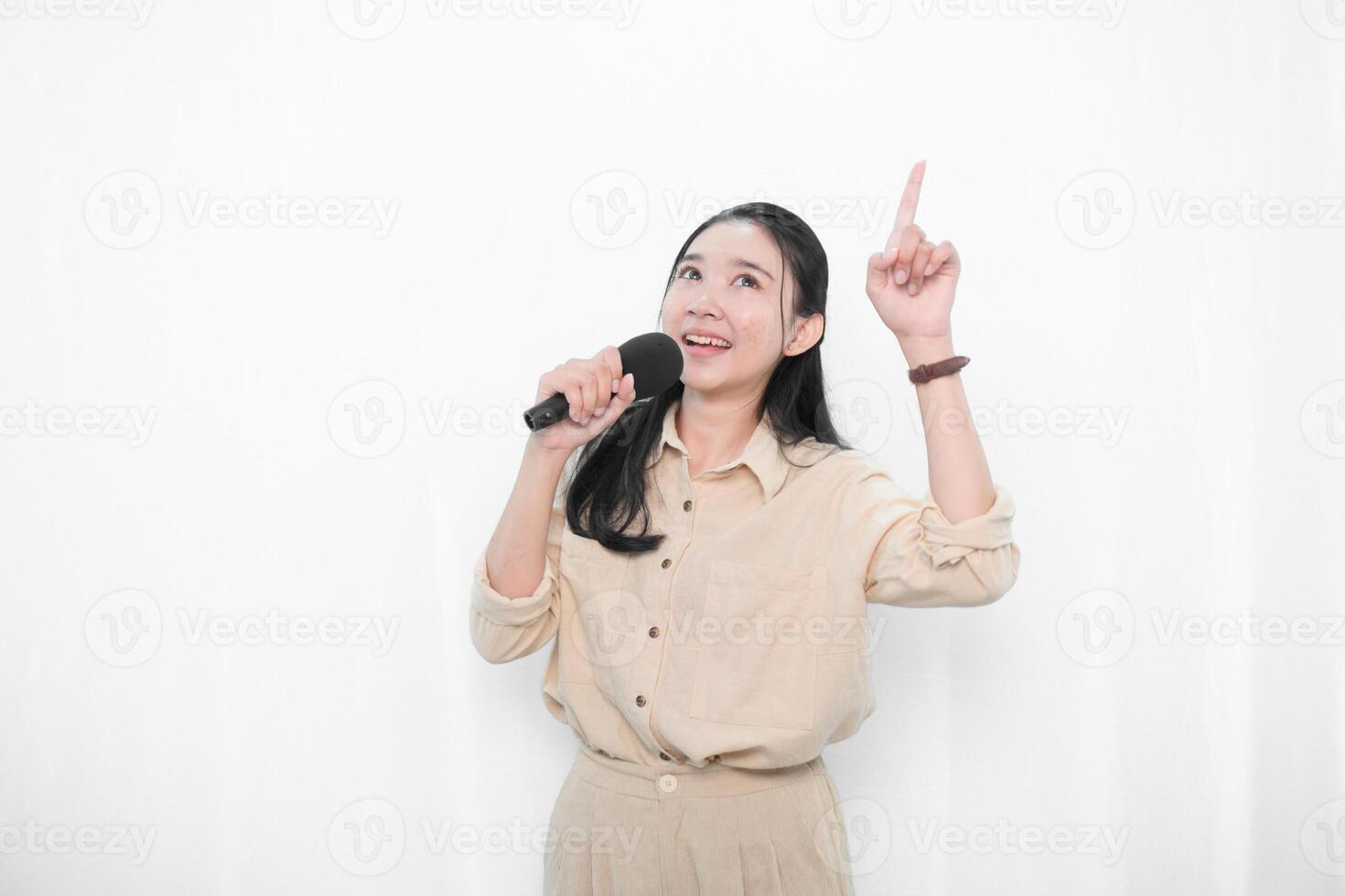 Expression of an Indonesian Asian model woman in white singing using a microphone photo