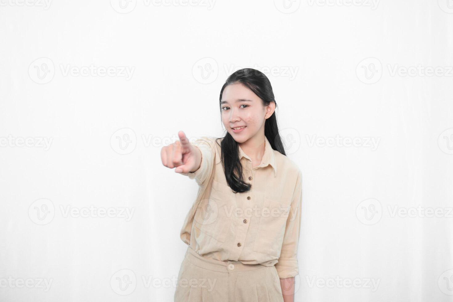 Expression of Indonesian Asian model woman in white dress smiling and pointing forward photo