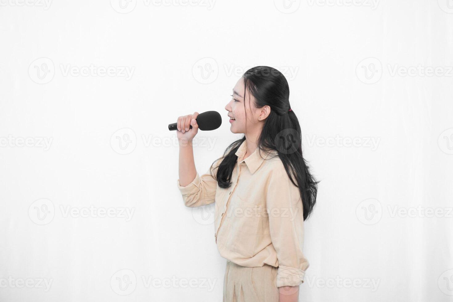 Expression of an Indonesian Asian model woman in white singing using a microphone photo