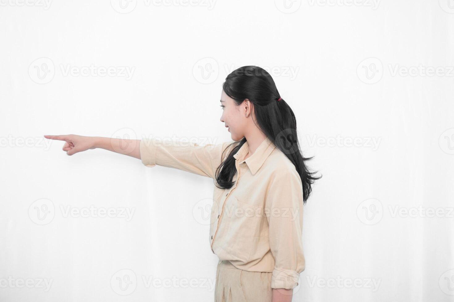 Expression of Indonesian Asian model woman in white dress smiling and pointing forward photo