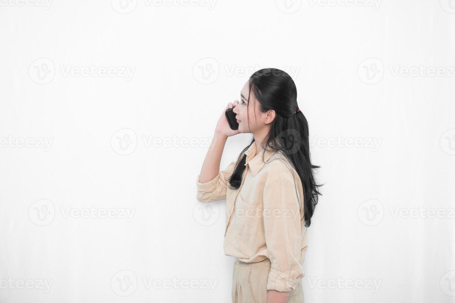 Expression of an Indonesian Asian model woman in white is making a phone call with a smartphone photo