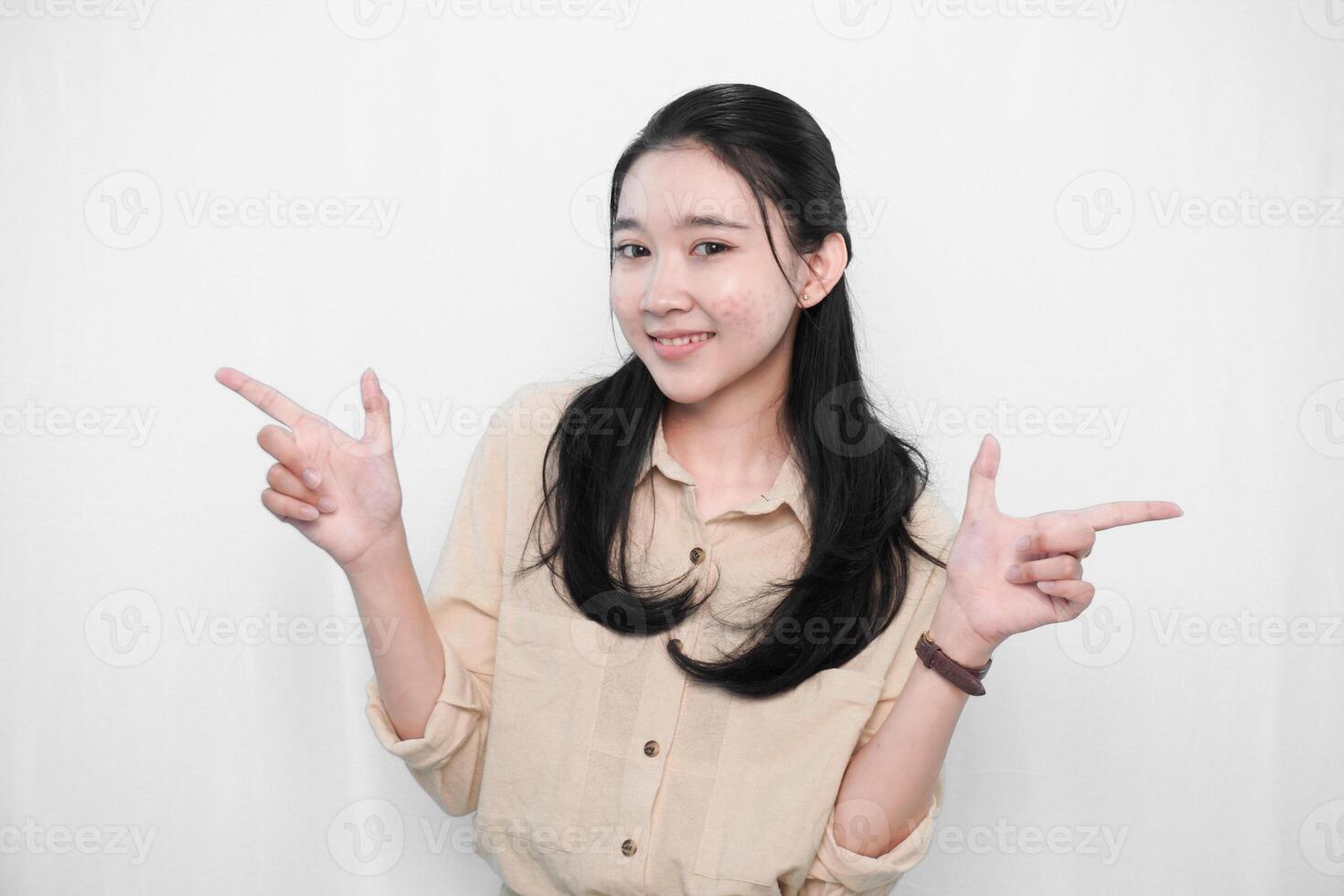 Expression of Indonesian Asian model woman in white dress smiling and making gun sign photo