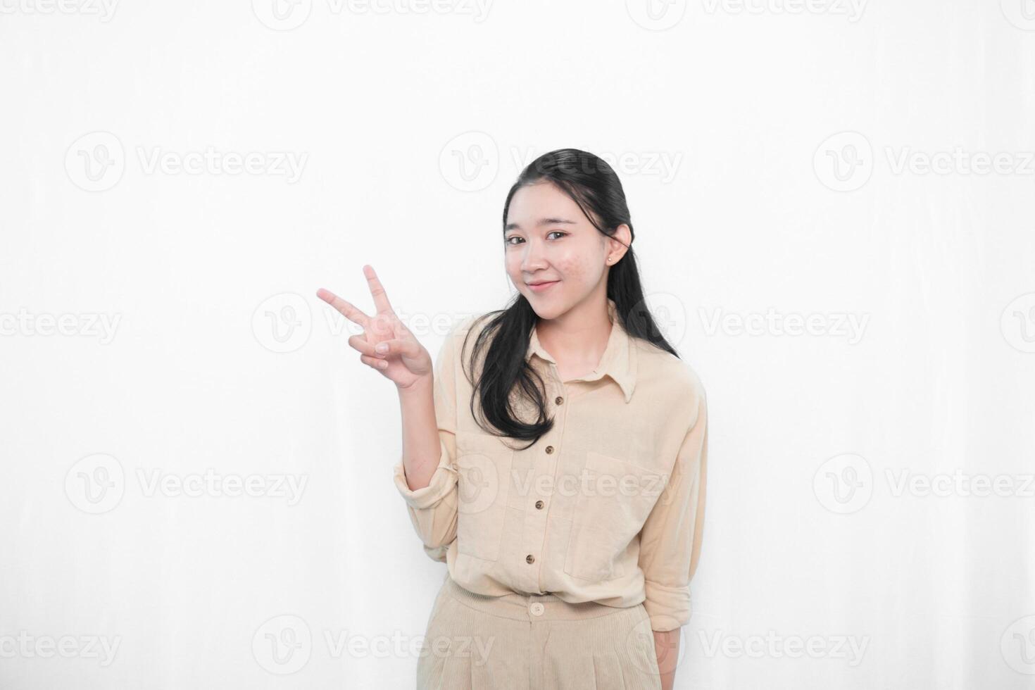 The expression of an Indonesian Asian model woman in white is smiling and making a peace code photo