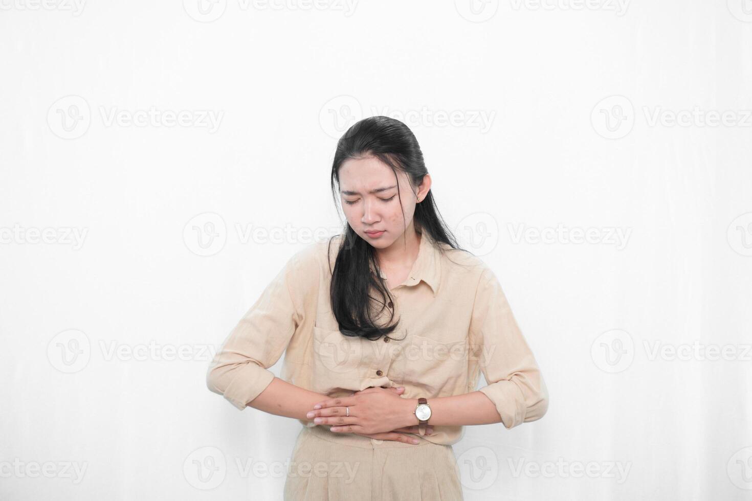 Expression of Indonesian Asian model woman in white dress having stomach ache photo