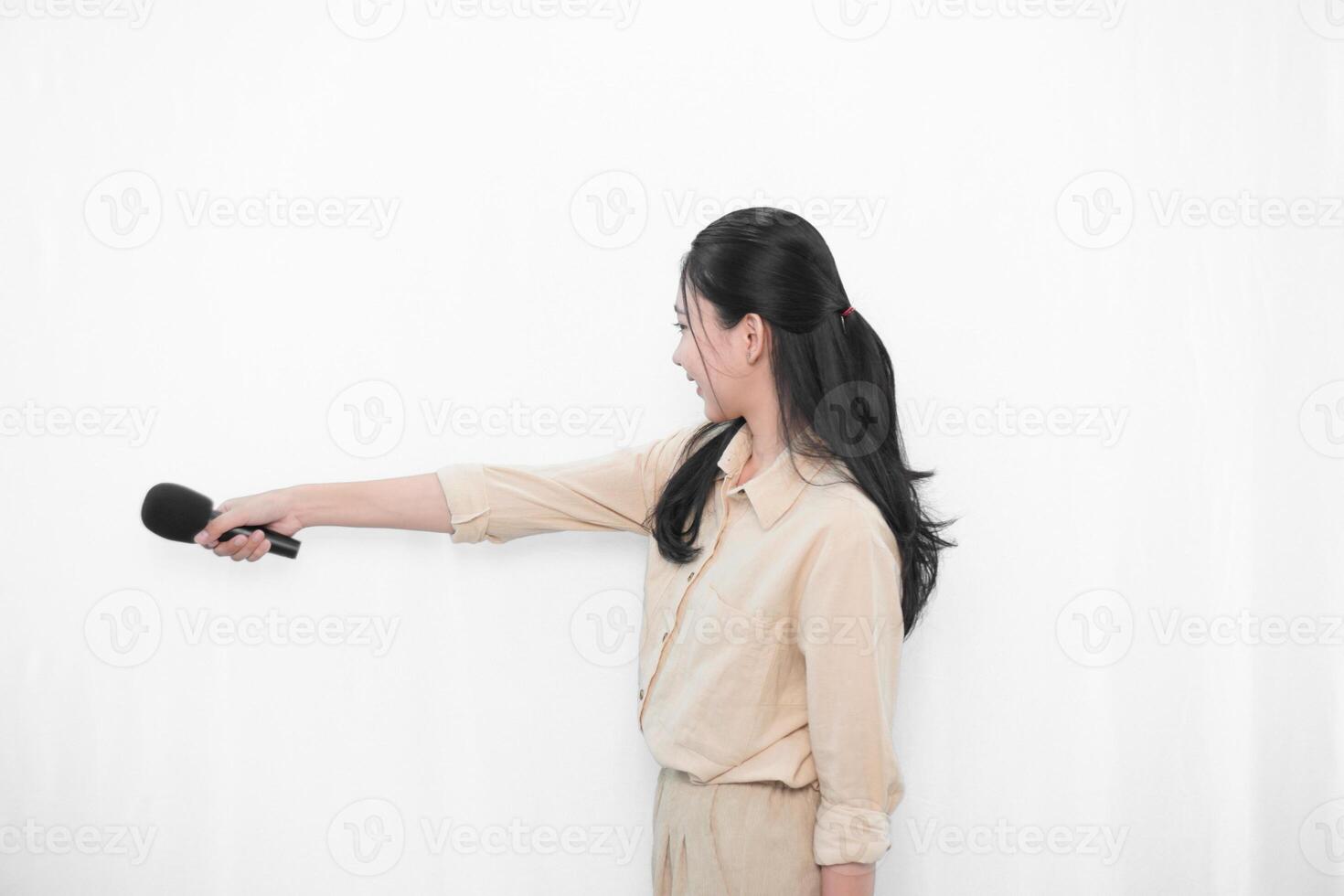 Expression of an Indonesian Asian model woman in white singing using a microphone photo