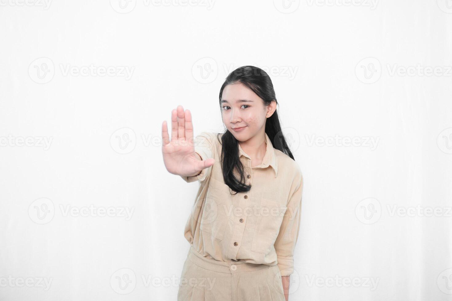 The expression of an Indonesian Asian model woman in white is smiling and making a stop sign photo