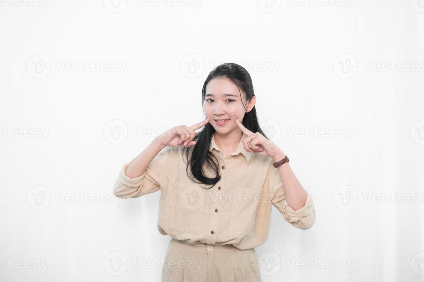 The expression of an Indonesian Asian model woman in white clothes smiling and putting her index finger to her cheek photo