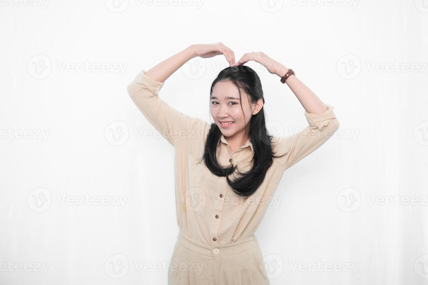 The expression of an Indonesian Asian model woman in white is smiling and making a love code photo