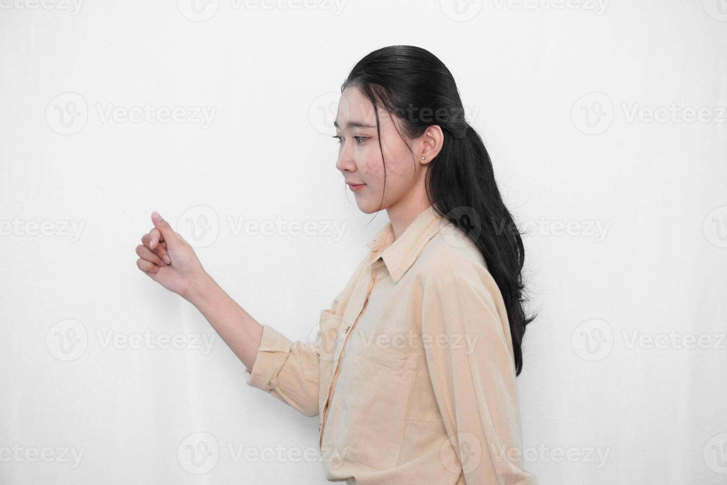 Expression of Indonesian Asian model woman in white dress smiling and making love sign with her fingers photo