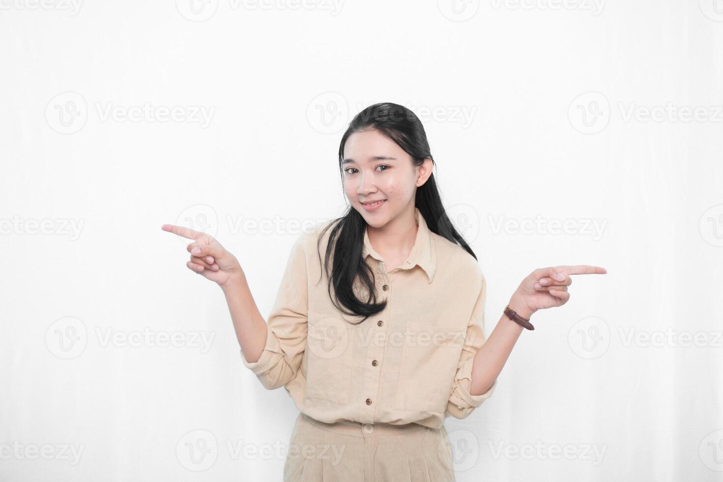 The expression of an Indonesian Asian model woman in white is smiling and making a gesture pointing to the side. photo