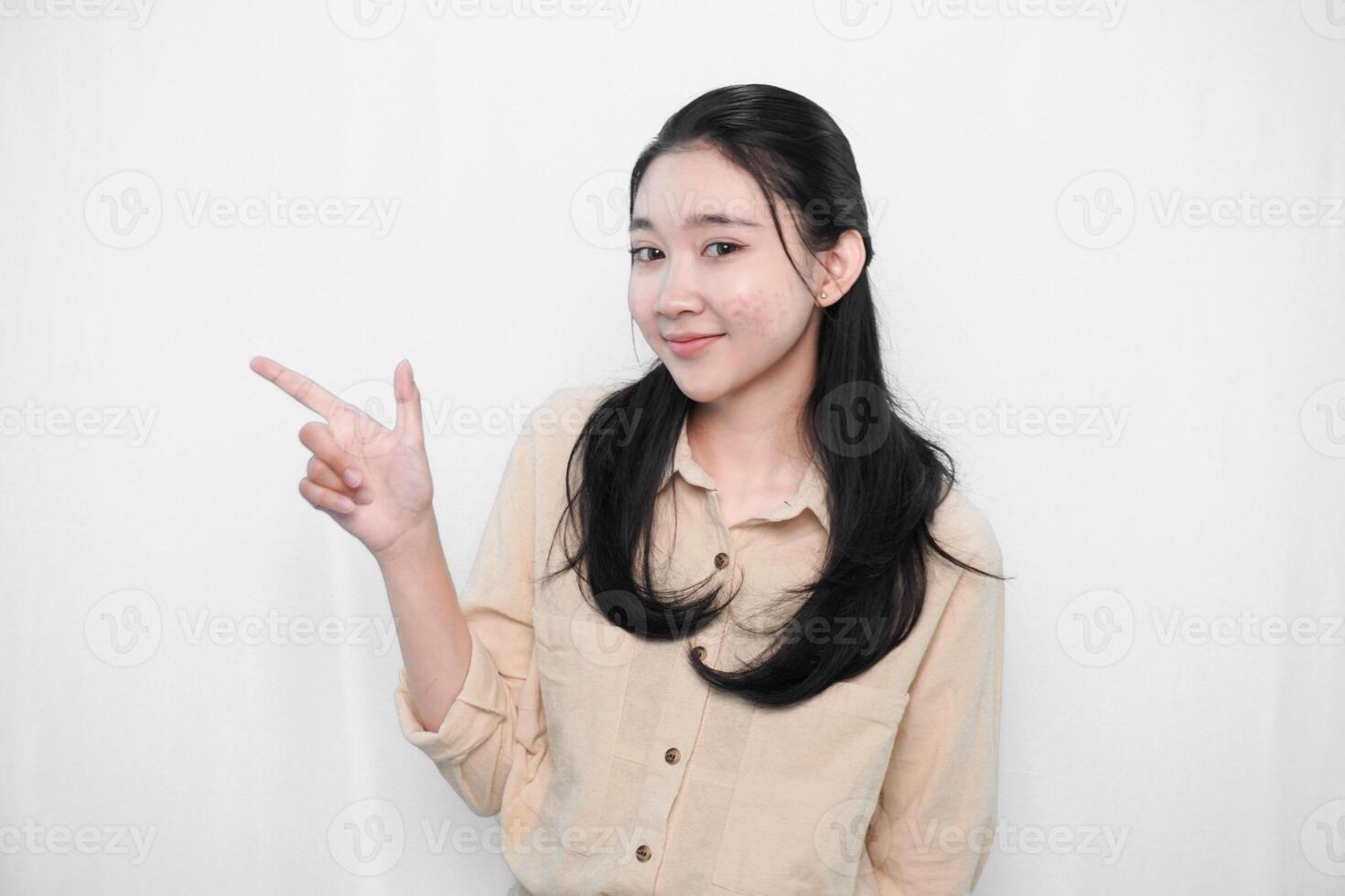 Expression of Indonesian Asian model woman in white dress smiling and making gun sign photo