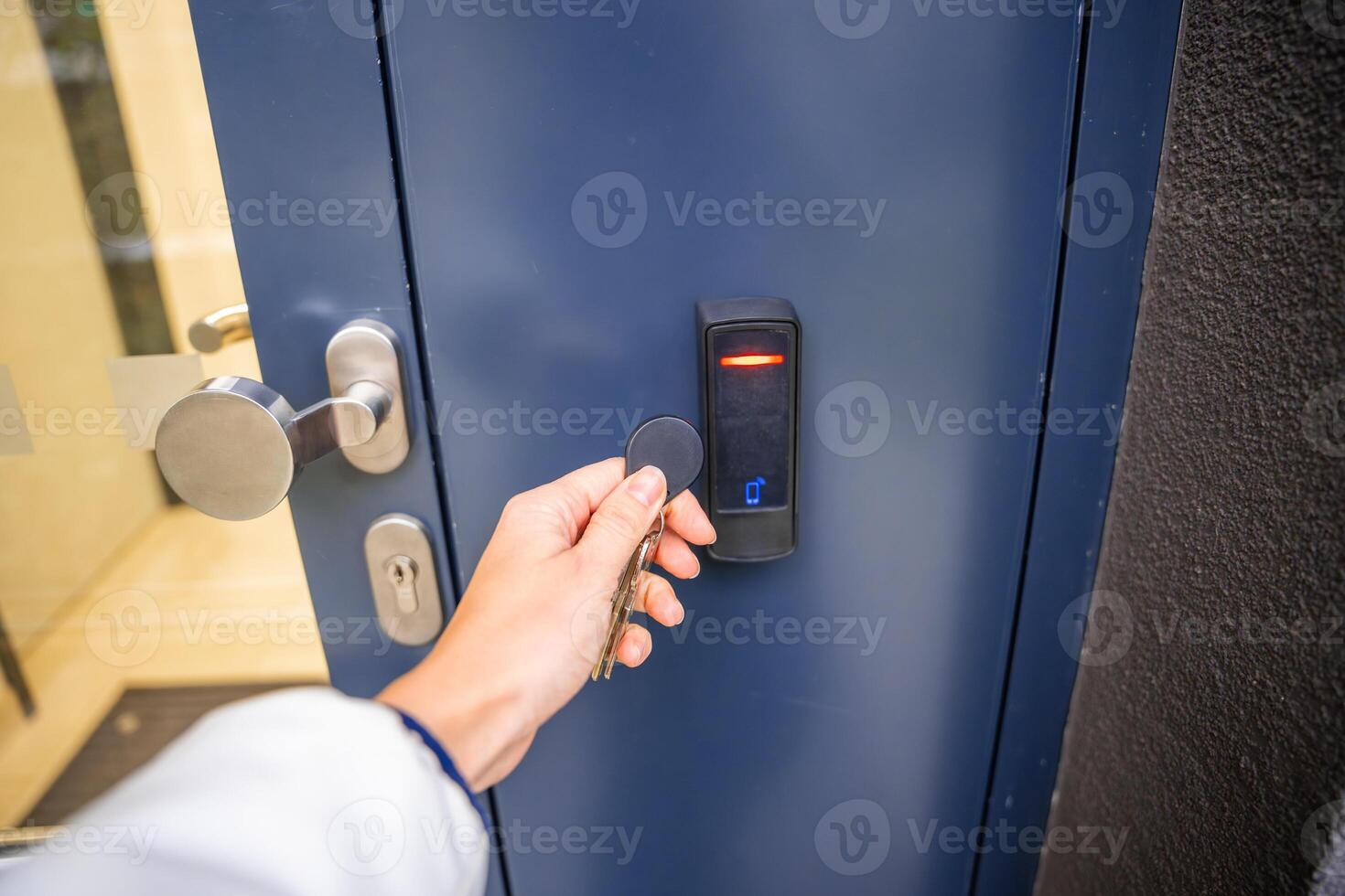 Close up view of person using a electric lock key fob to access a building via a reader of entry system mounted on a house wall. High quality photo